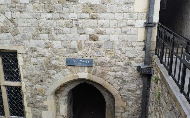 stone frontage of a building with a sign that says Bloody Tower above the arched entrance