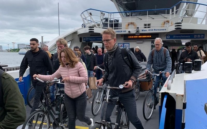 commuters pushing their bikes off a busy ferry in the middle of winter