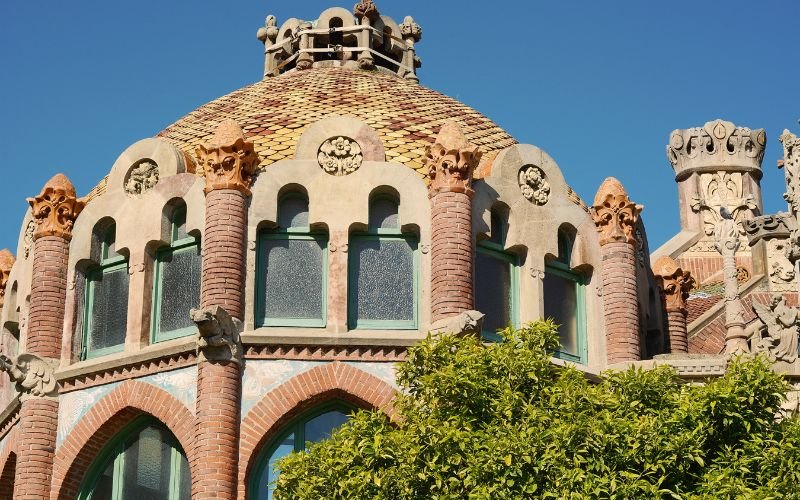 majestic dome staped building with arch windows and red and white brick with green foliage in the forefront
