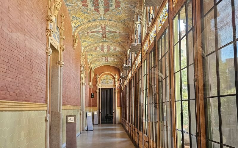 passage way featuring floor to ceiling windows on one side with arch doorways on the other and a decorative tiled ceiling