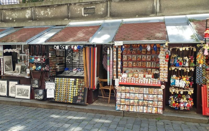 row of market stalls selling souvenirs that are all different colours displayed on tables and leaning on boards infront of the market stall