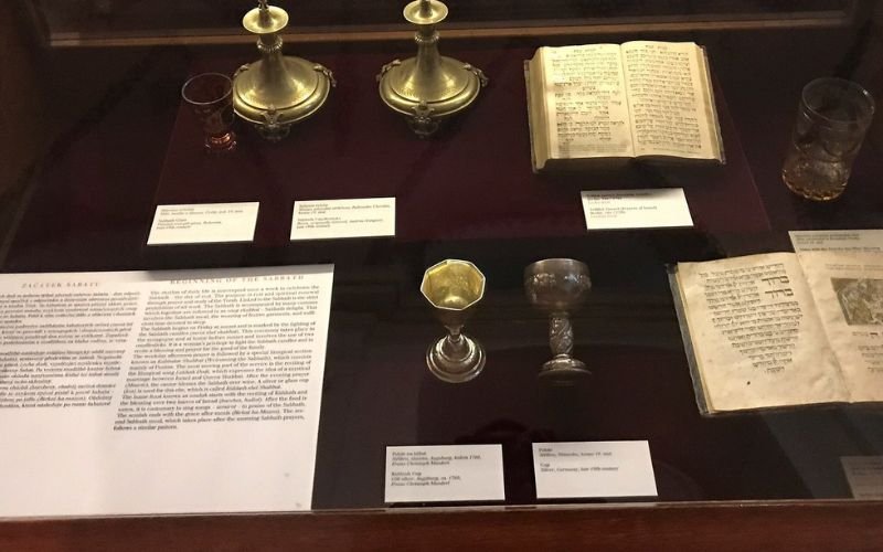 display of historic artifacts including brass cups and an old book displayed in a glass cabinet