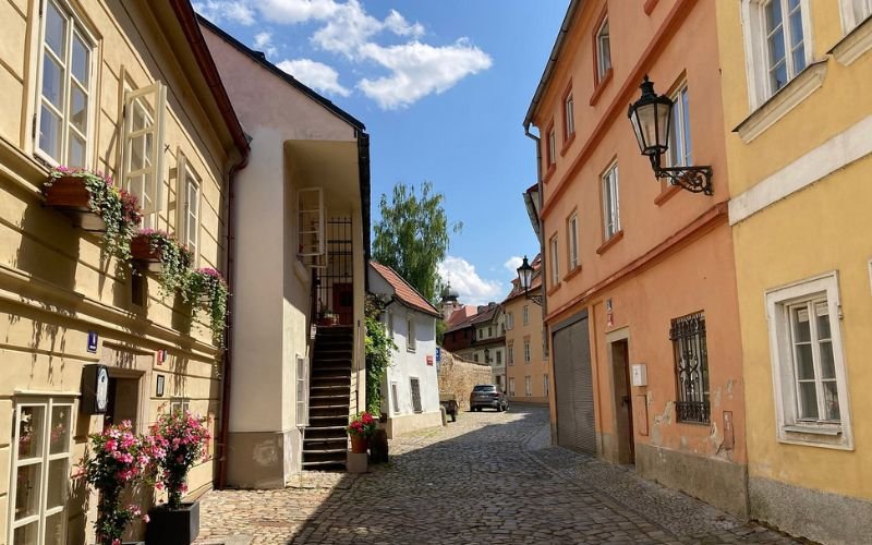 rows of pastel coloured ancient houses with white french windows and a cobbleston lane