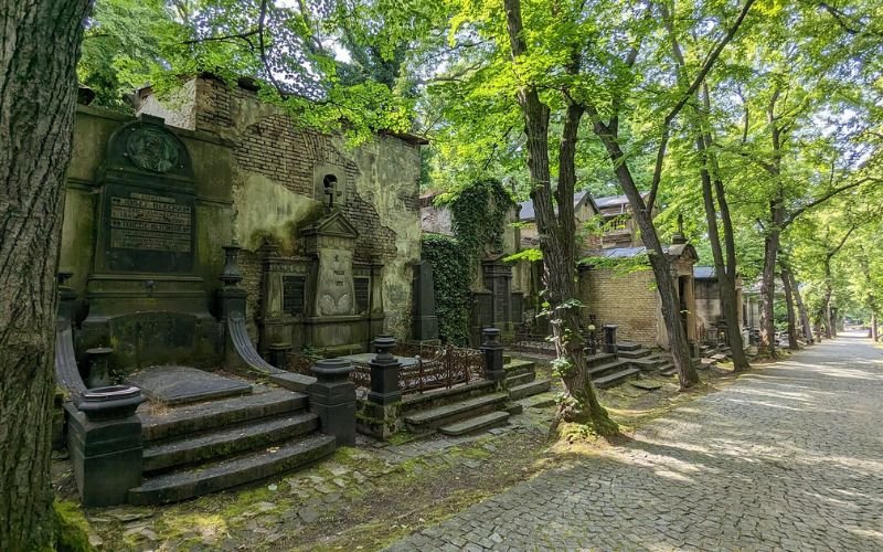 cemetary gardens with several large headstones surrounded by large lush green trees